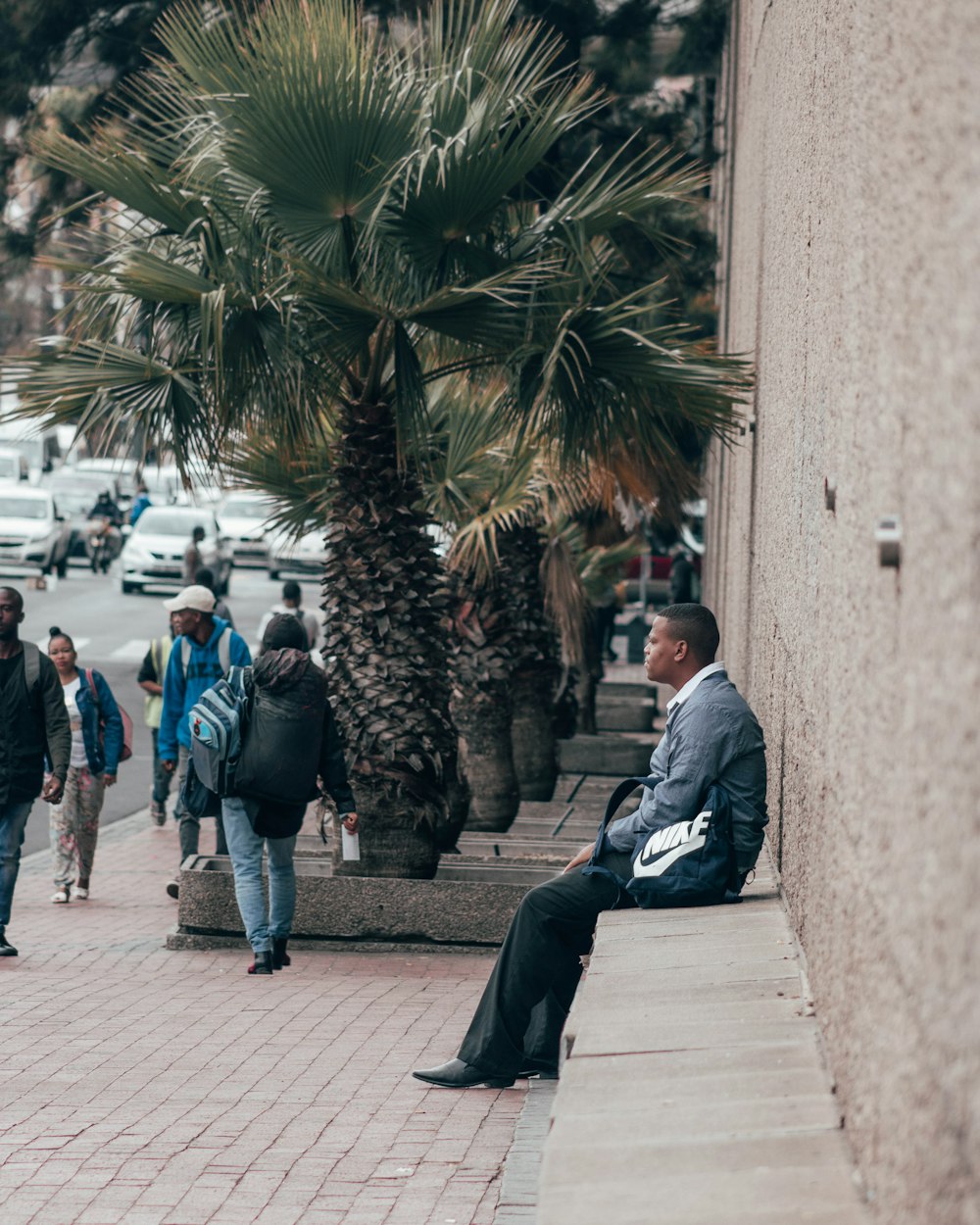 man in blue jacket sitting on concrete bench