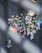 A vibrant marching band dressed in colorful, patterned costumes with white hats. They are playing various brass instruments like trombones, saxophones, and trumpets. One member holds a multicolored umbrella, adding to the lively scene on a city street.