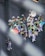 A vibrant marching band dressed in colorful, patterned costumes with white hats. They are playing various brass instruments like trombones, saxophones, and trumpets. One member holds a multicolored umbrella, adding to the lively scene on a city street.