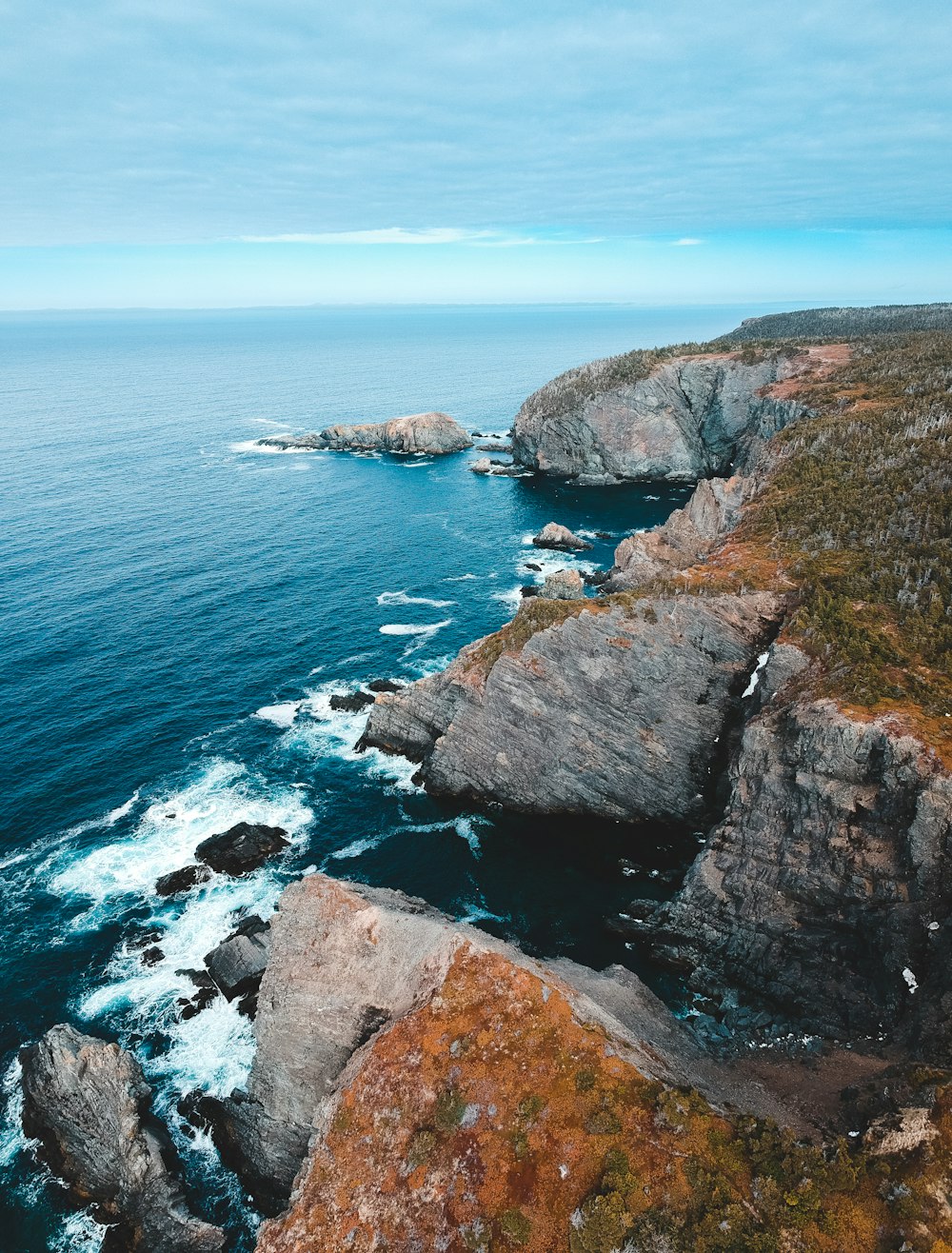 brown and green rock formation beside blue sea during daytime