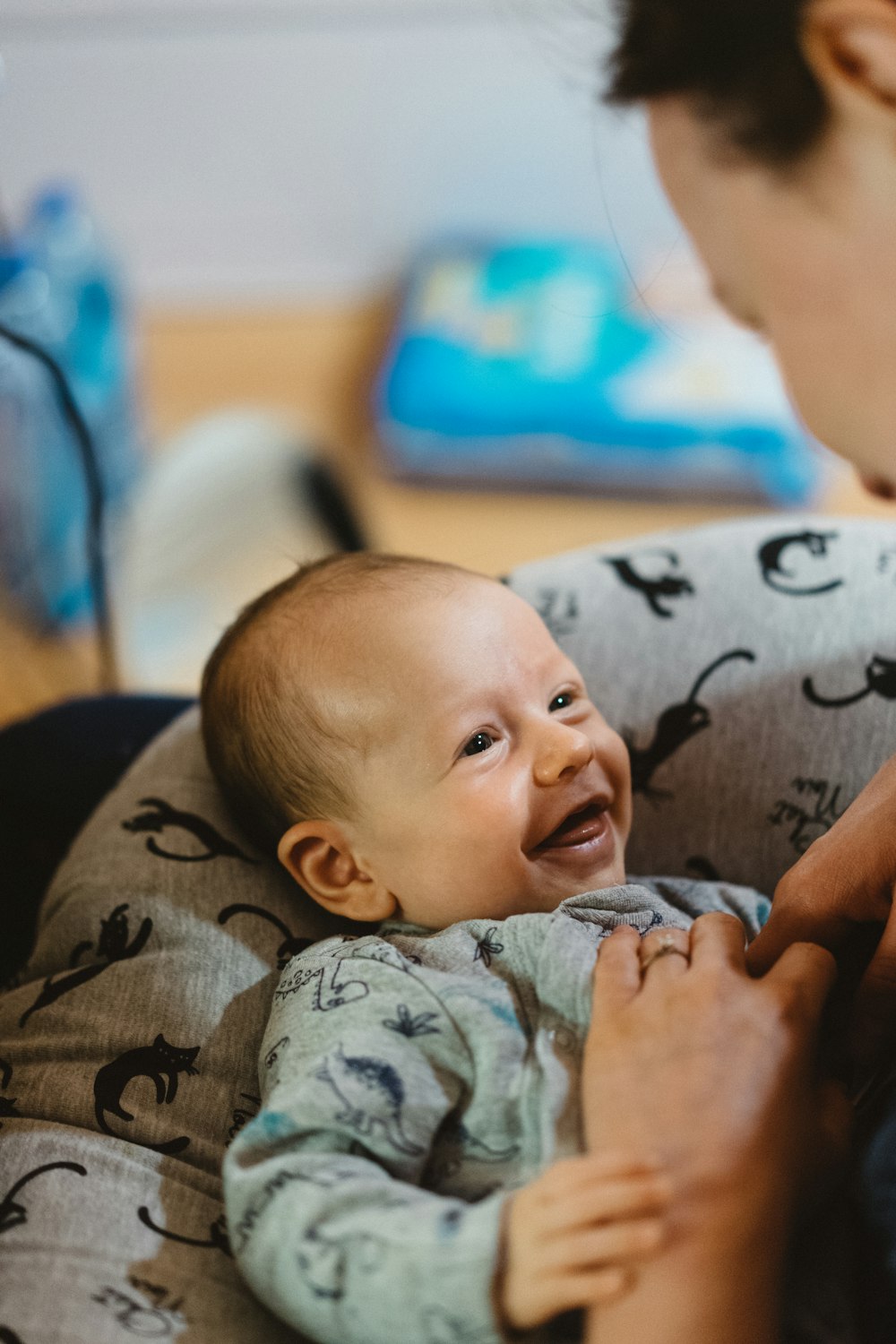 baby in grey and black camouflage onesie lying on bed