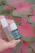 A close-up of a hand holding a small amber glass bottle filled with aromatic essential oil, surrounded by fresh herbs.
