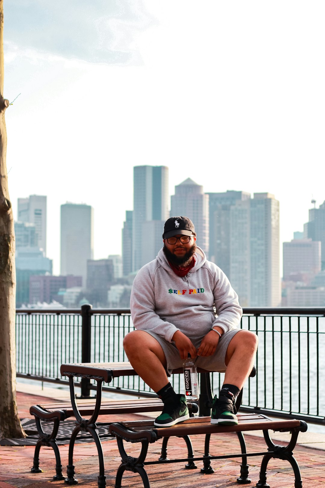 man in gray hoodie sitting on brown wooden bench during daytime