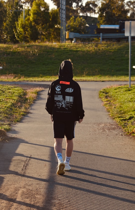 woman in black hoodie running on road during daytime in Canberra Australia