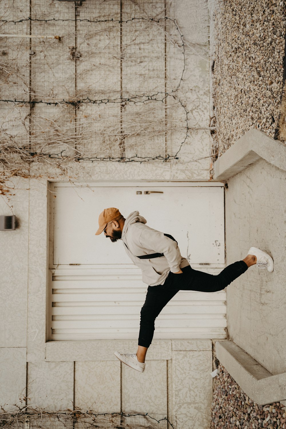 Hombre con camisa blanca de manga larga y pantalones negros saltando sobre una pared de hormigón blanco durante el día