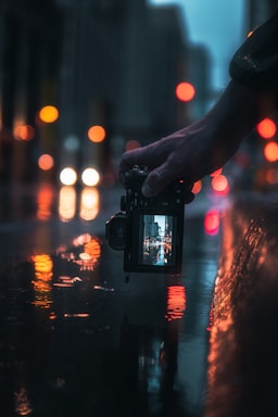 A close-up of a model's hand holding a camera, capturing vibrant Mumbai street scenes.