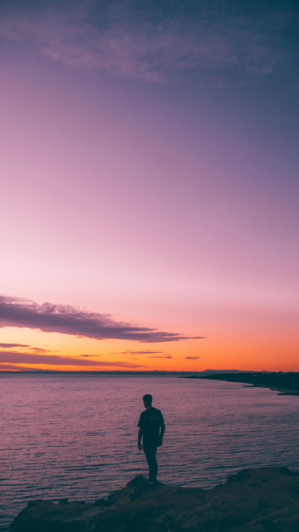 silhouette of person standing on beach during sunset