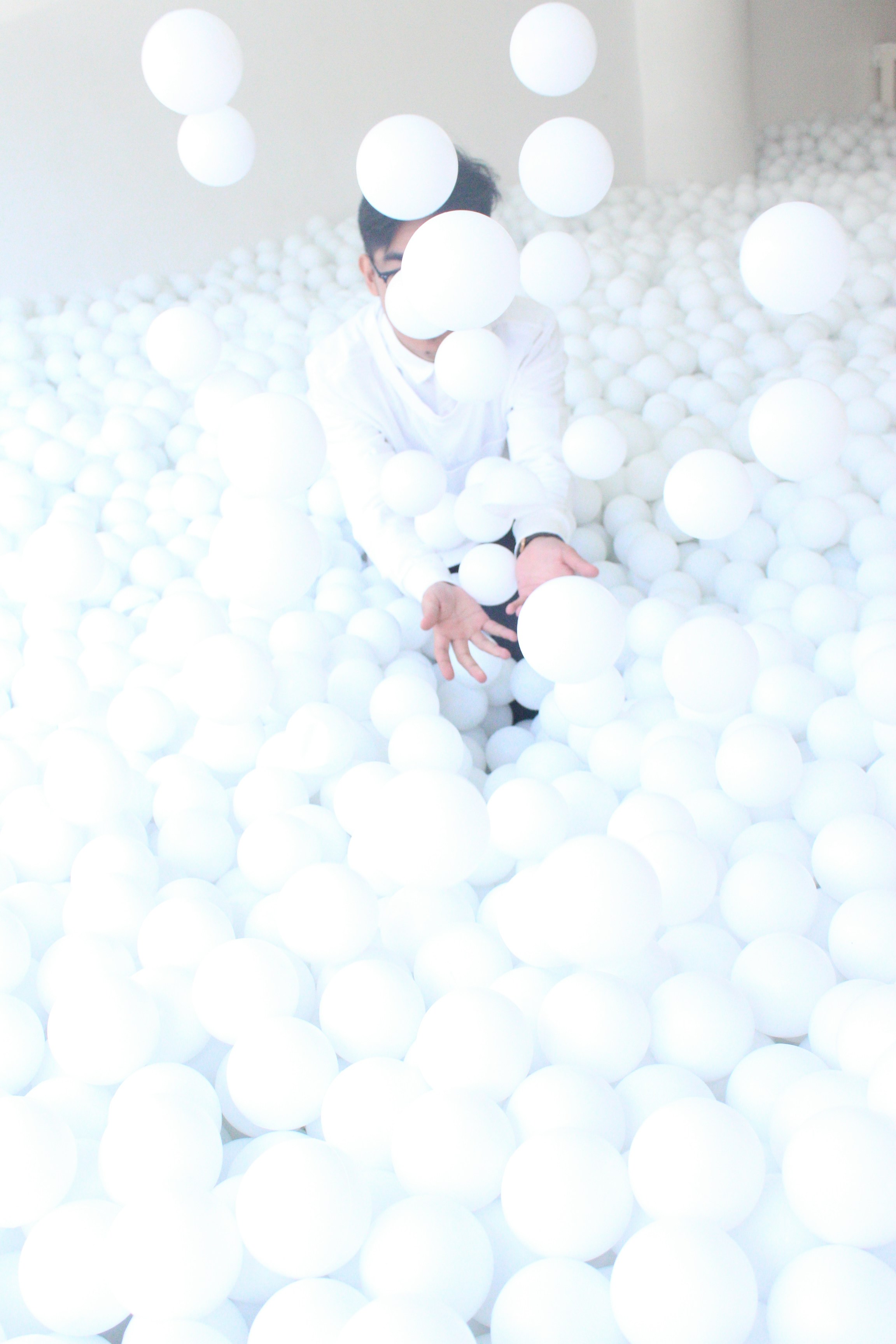 woman in white coat and white hijab standing on white round balloons