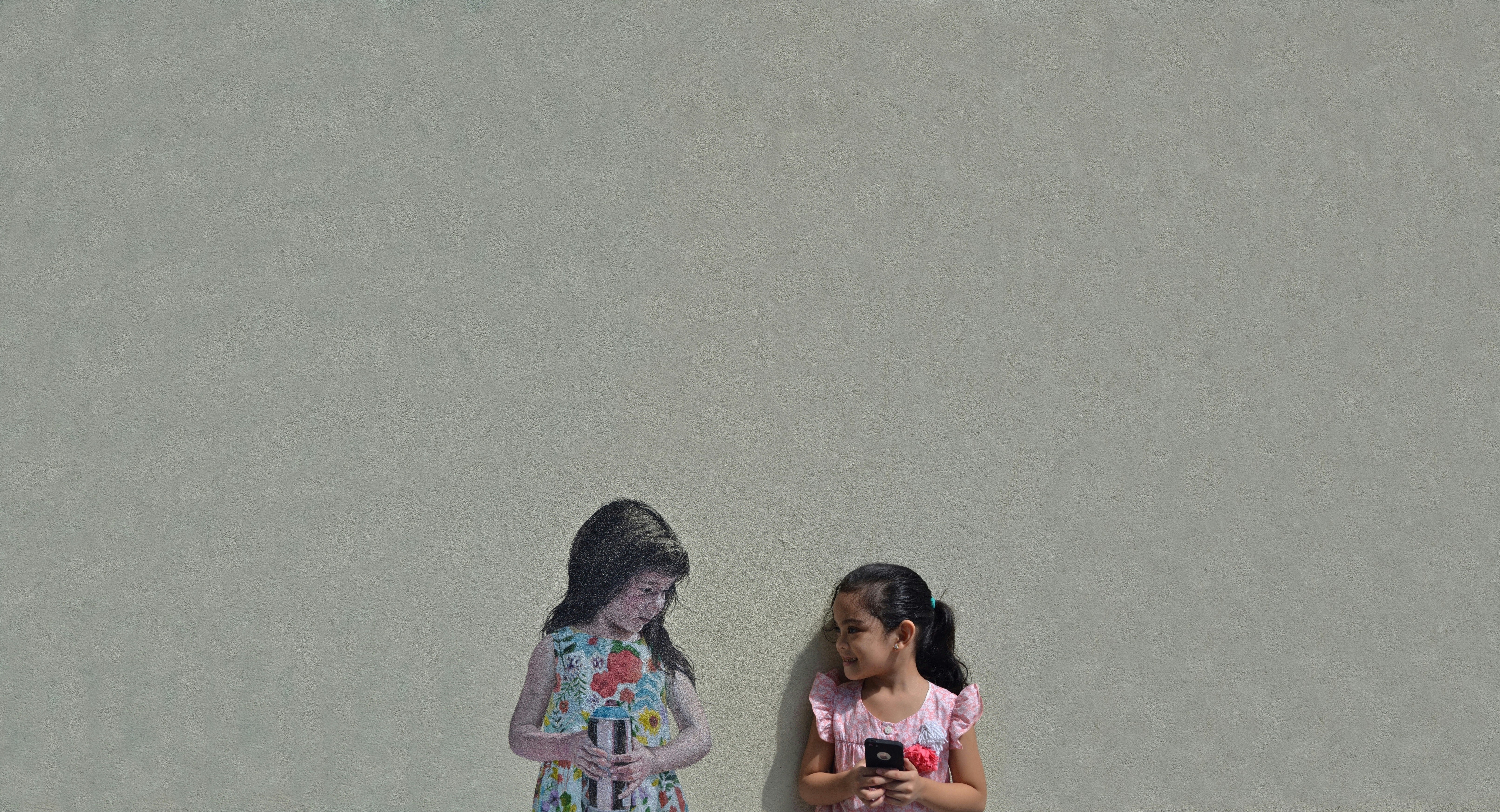 2 women standing beside wall