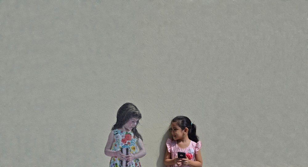 2 women standing beside wall