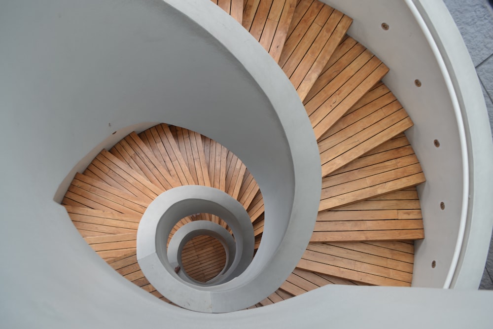 Escalera de caracol de madera marrón con pared blanca