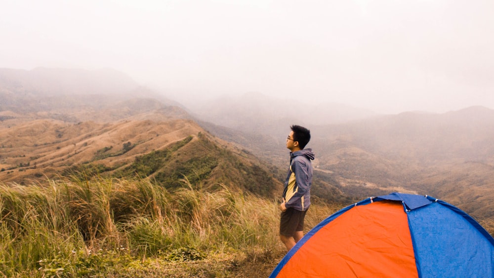 woman in brown jacket standing near orange tent during daytime