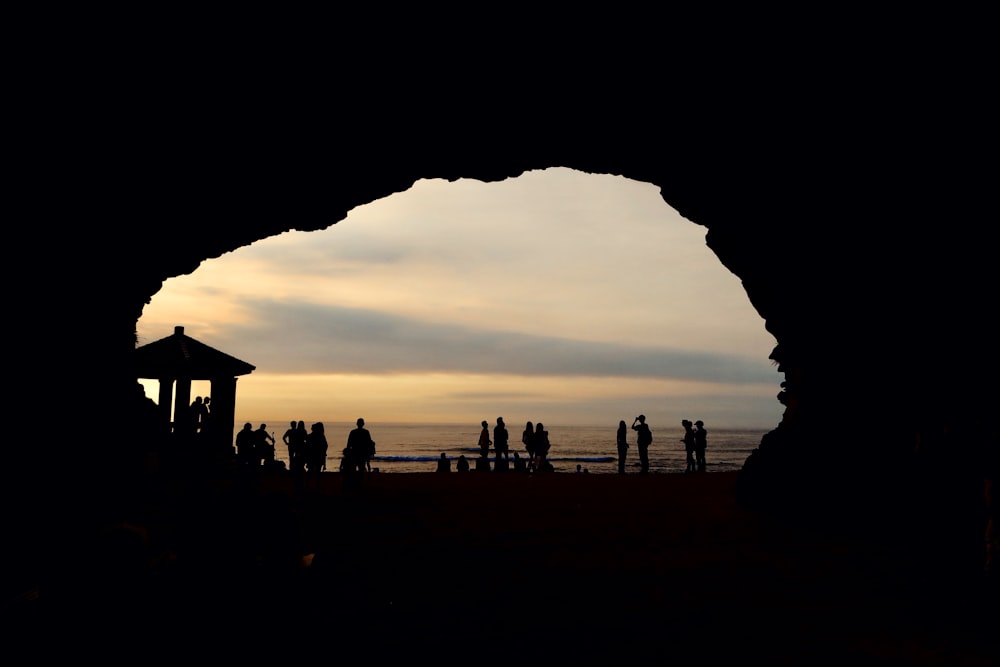 silhouette of people standing on beach during sunset