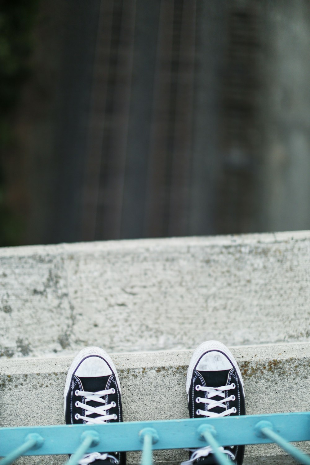 person wearing black and white sneakers standing on gray concrete pavement
