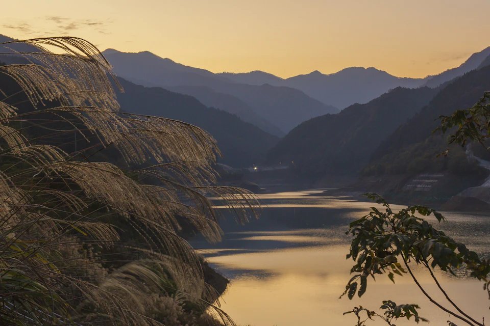 Serene mountain landscape at sunset with two majestic peaks against a clear blue sky