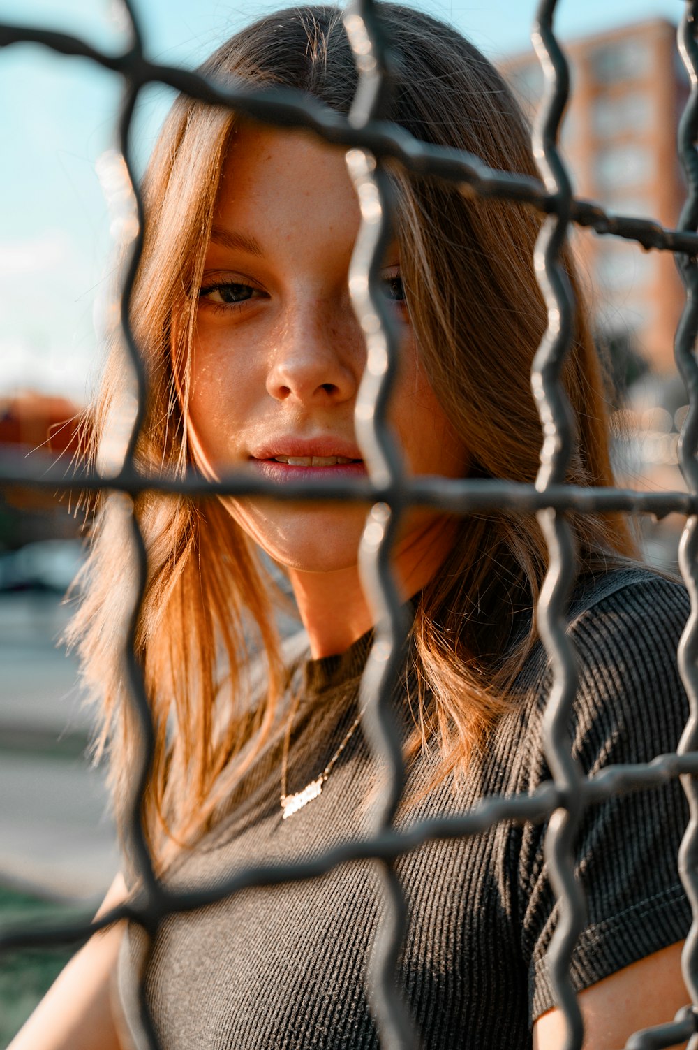 woman in black and white striped shirt leaning on gray metal fence during daytime
