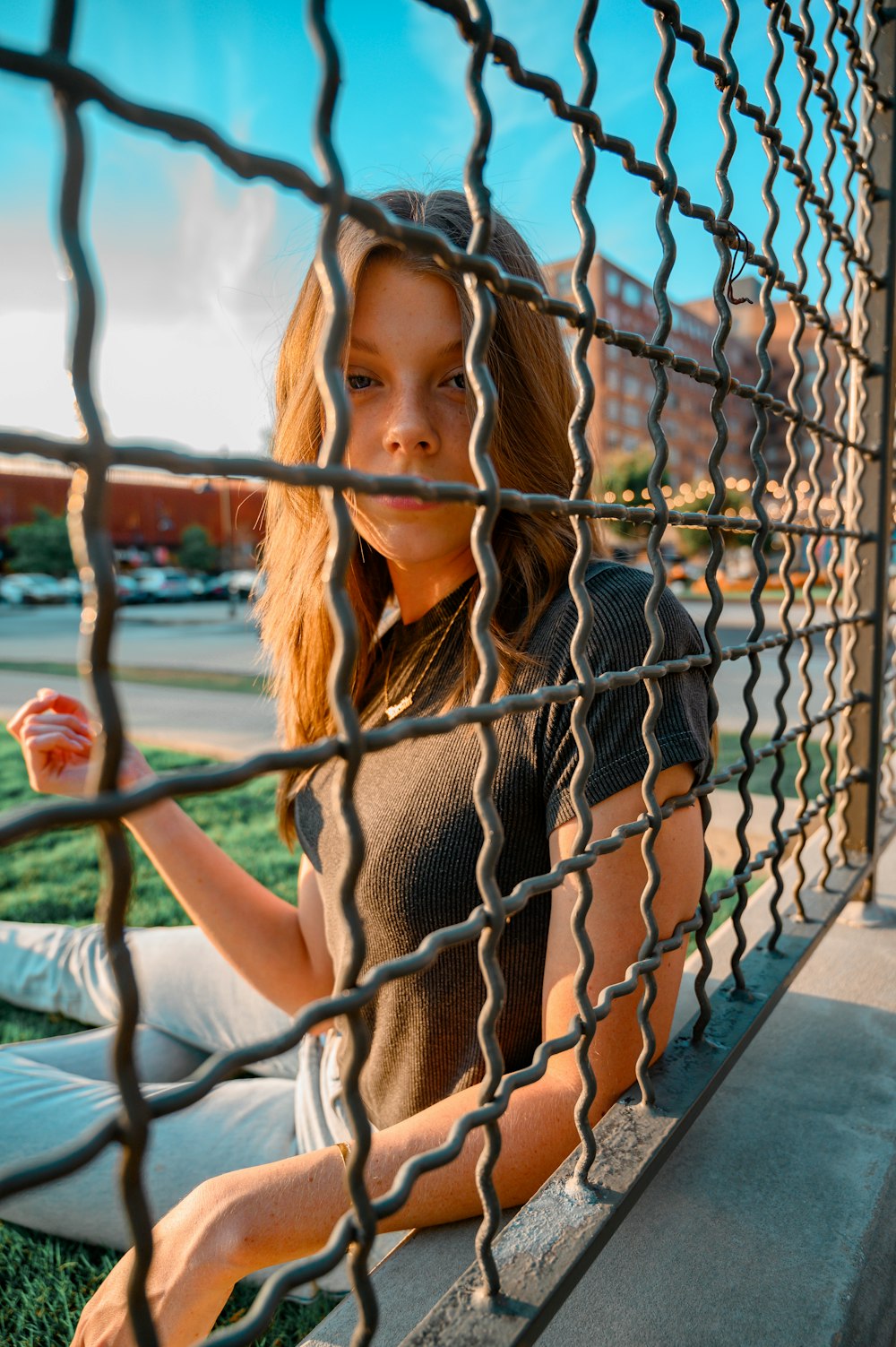 woman in black and white stripe shirt leaning on chain link fence during daytime