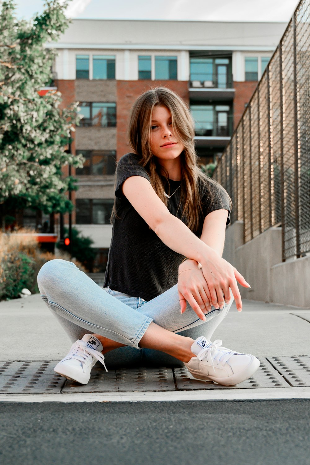 woman in black shirt and gray denim jeans sitting on concrete floor