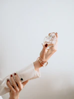 A sophisticated woman applying perfume in a modern, minimalistic room with golden accents.