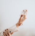 person in white dress holding clear glass bottle