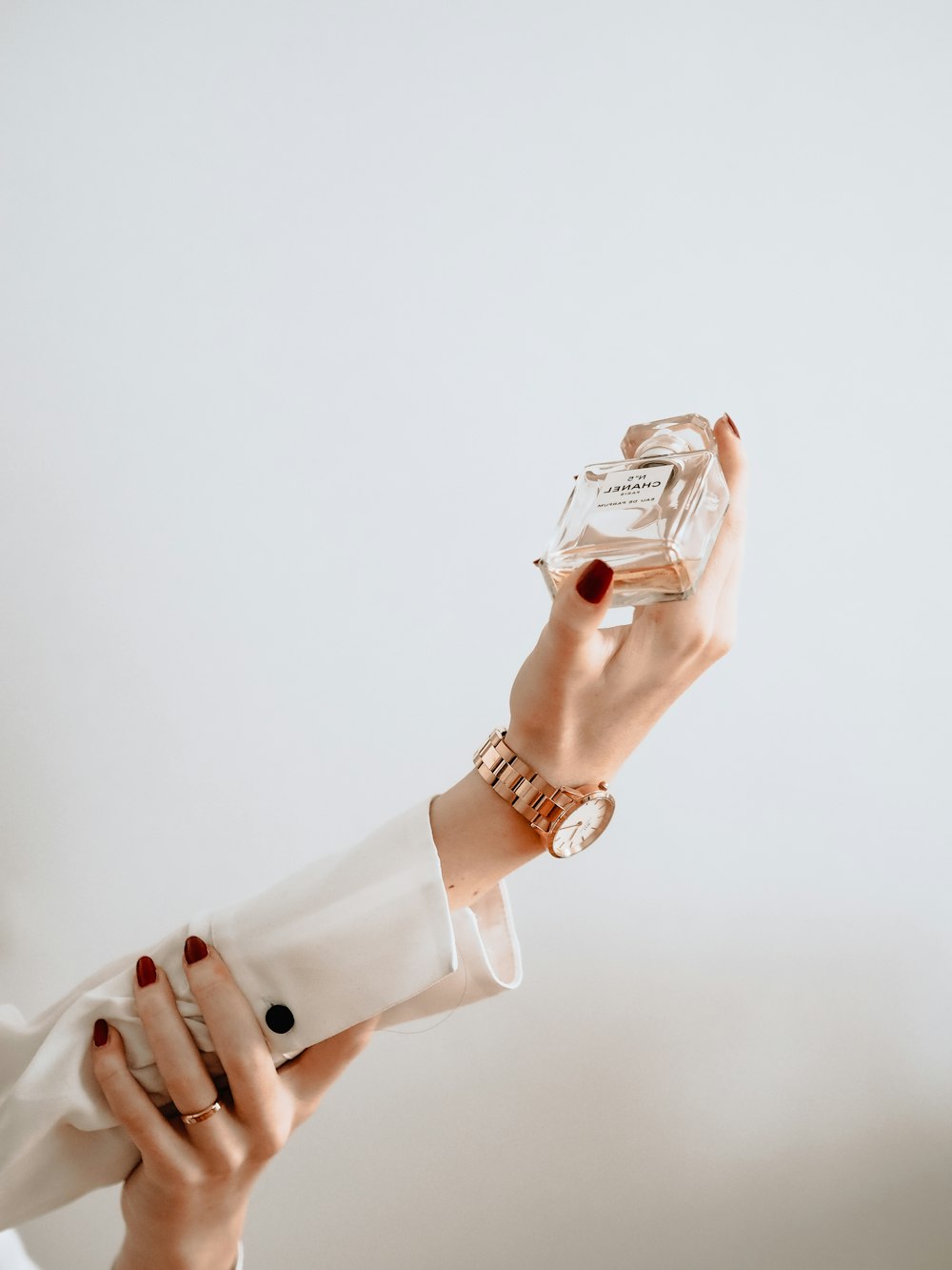 Persona en vestido blanco sosteniendo una botella de vidrio transparente