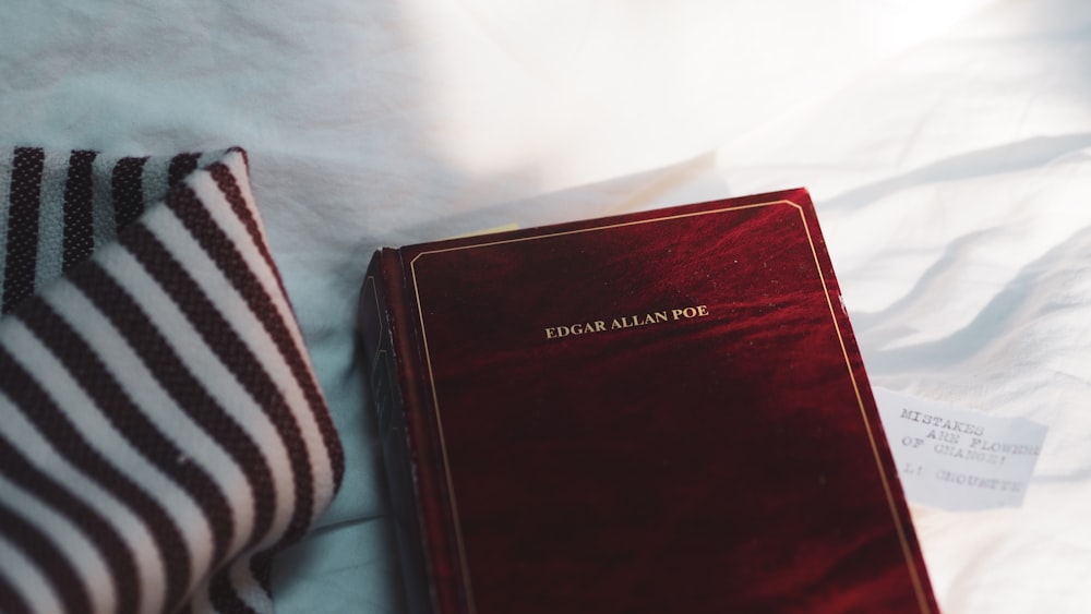 red hardbound book on white textile