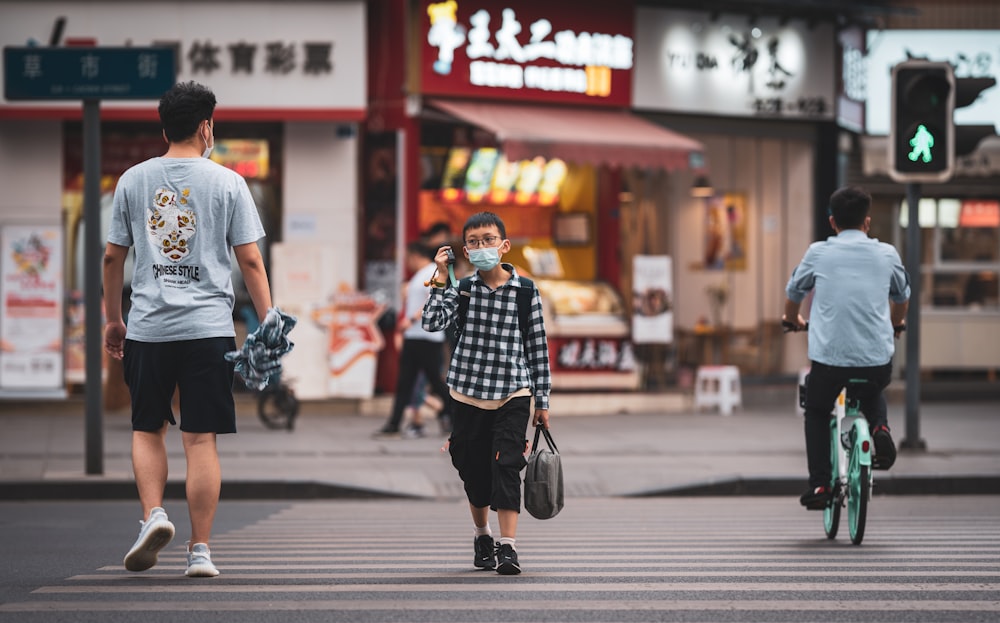 man in white t-shirt and black and white checked skirt walking on pedestrian lane during