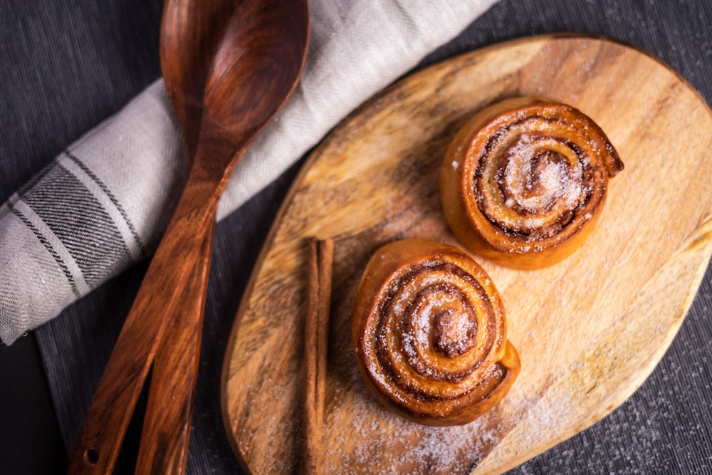 three brown doughnuts on brown wooden plate