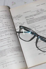 Mathematics textbook open with handwritten notes and a calculator nearby.