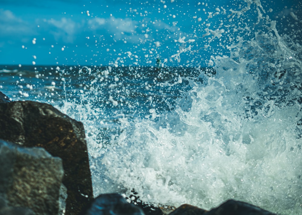 ocean waves crashing on rocks under blue sky during daytime