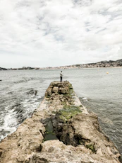 gray concrete dock on body of water under cloudy sky during daytime