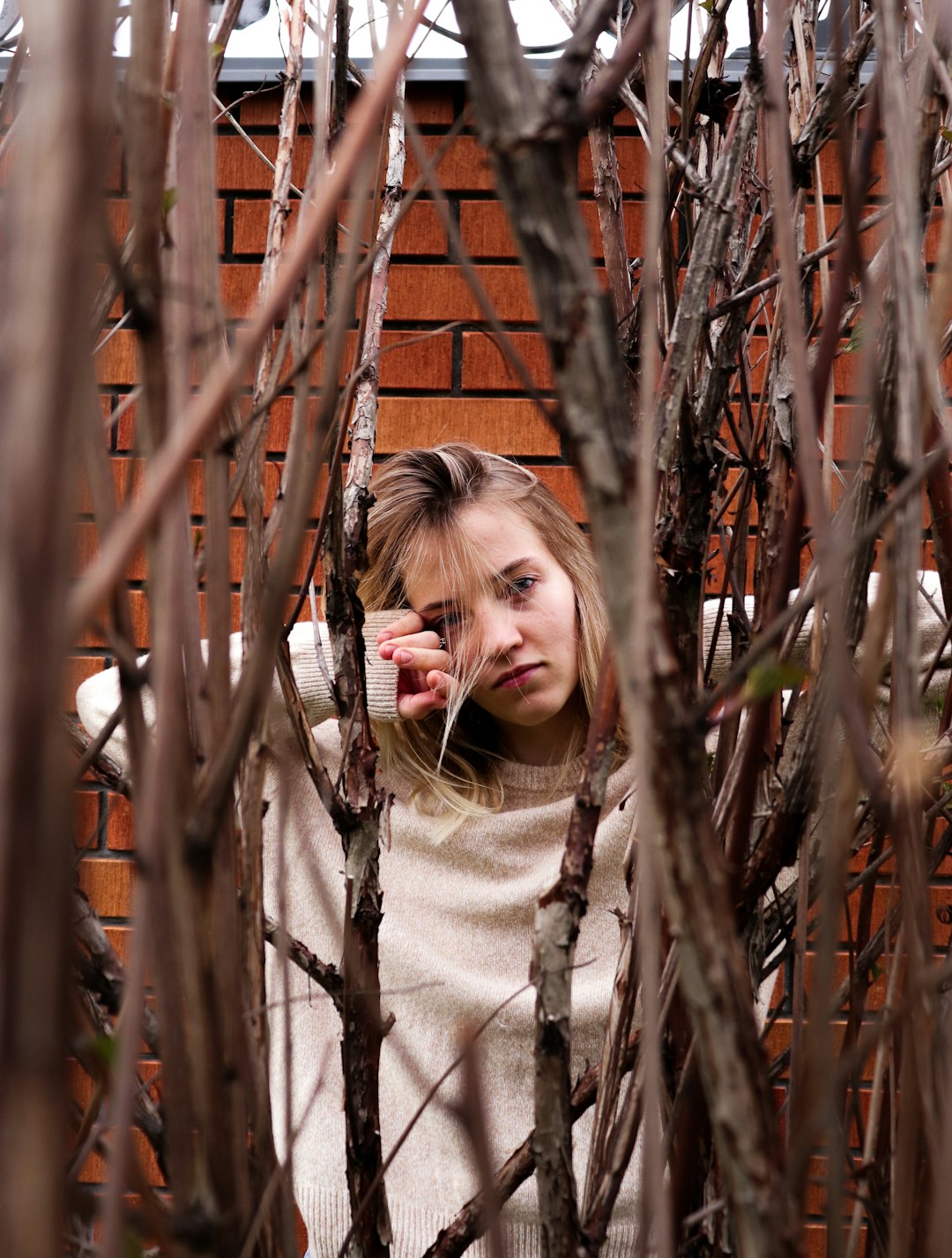 girl in white sweater standing beside brown metal fence during daytime