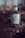 A bottle of premium dry gin with a textured glass design is placed on a natural backdrop. The label features a deer motif and intricate patterns. The scene is softly lit, casting a muted and calm ambiance.