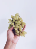 Hands holding a variety of fresh fruits against a white background.