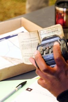 Close-up of hands processing payroll documents with a calculator and computer