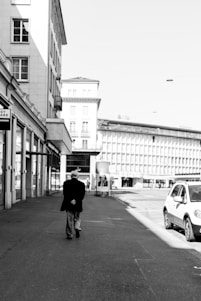 Monochrome photo of a focused man walking through an urban street at dawn, dressed in sleek black and white apparel.