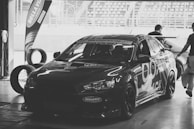 Team members discussing a maintenance plan beside a sleek black vehicle.