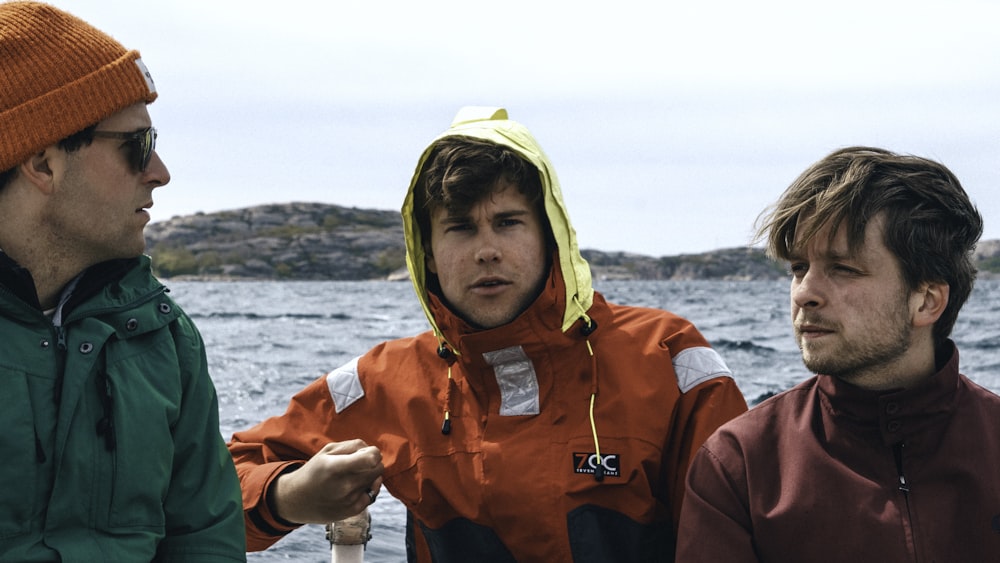 man in orange hoodie standing on rock during daytime