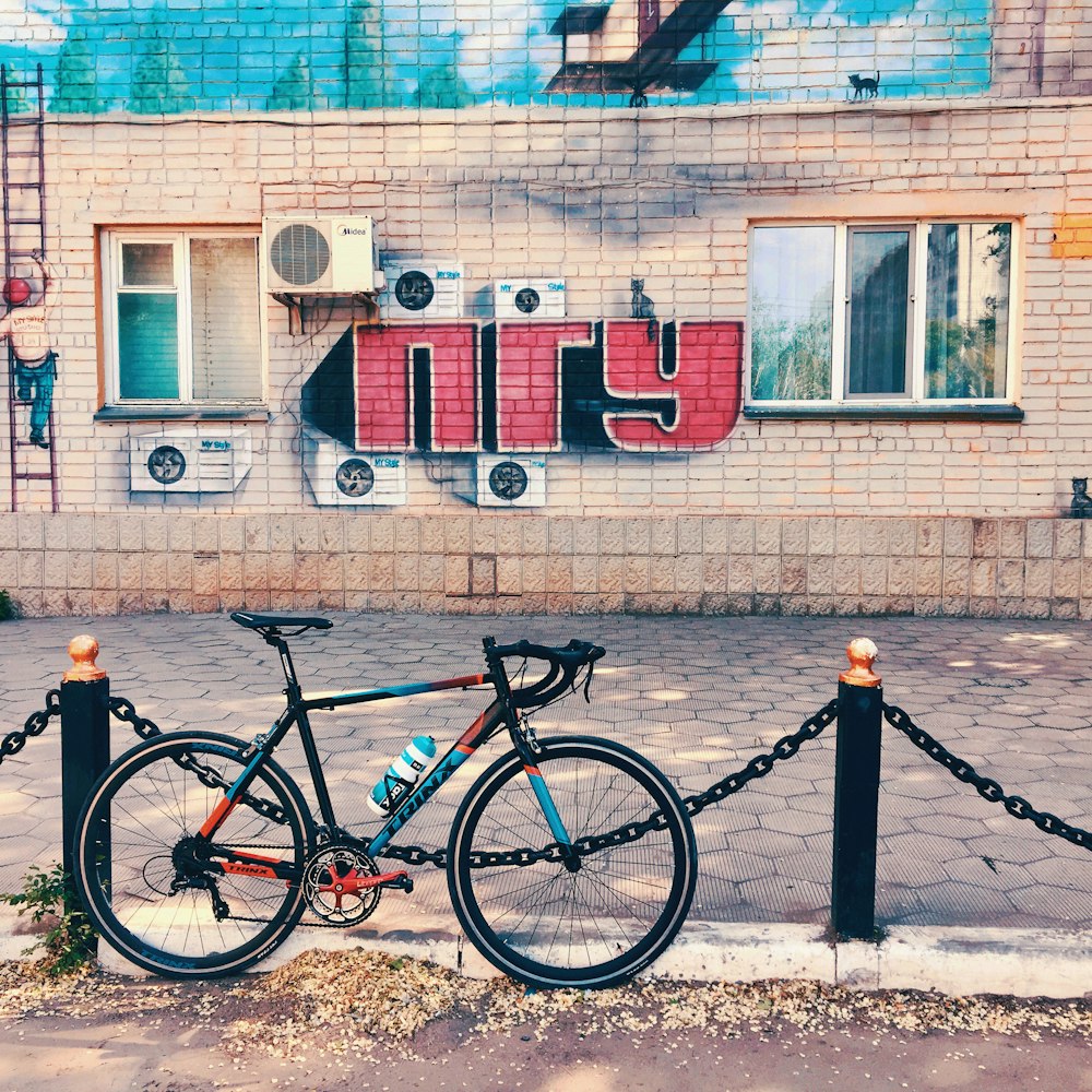 black bicycle parked beside blue and white concrete building