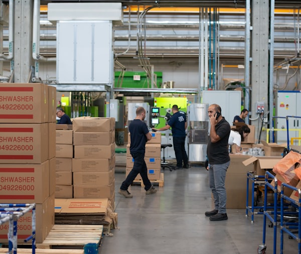 man in gray shirt standing beside brown cardboard boxes