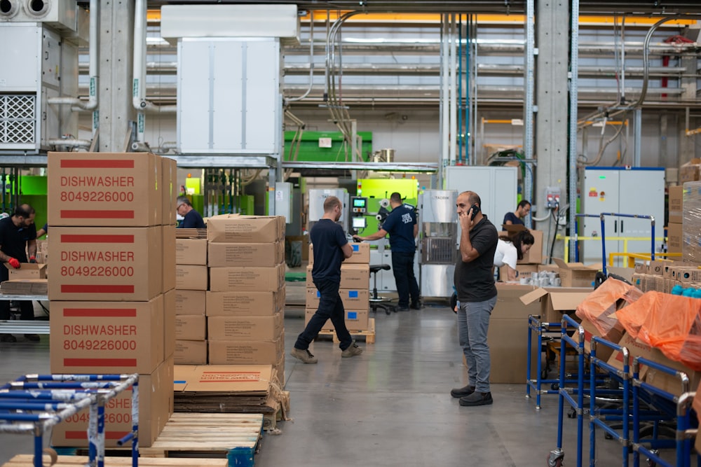 man in gray shirt standing beside brown cardboard boxes