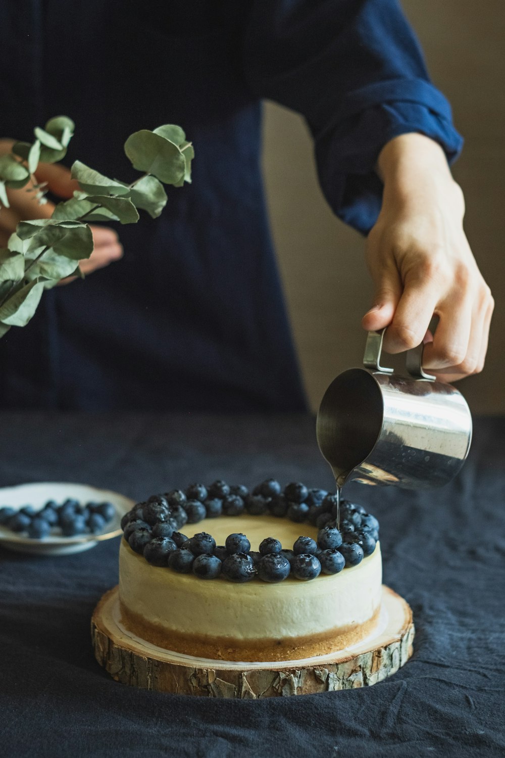 person pouring white cream on white and brown cake