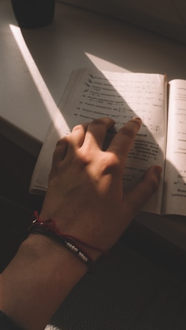 A smiling woman wearing a sleek silver bracelet, her hand resting gently on a vintage book