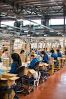 Factory floor with workers carefully inspecting compressed mattresses before packaging.