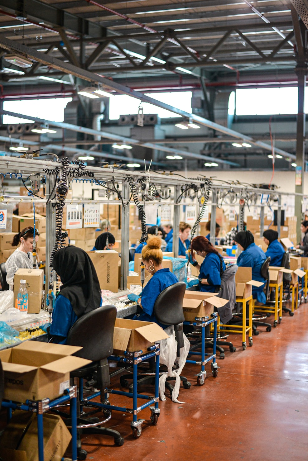 Manufacturing assembly line with workers at individual workstations packaging products