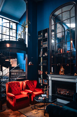 A luxury living room showcasing elegant marble white flooring, royal blue velvet sofas, and matte black lighting fixtures.