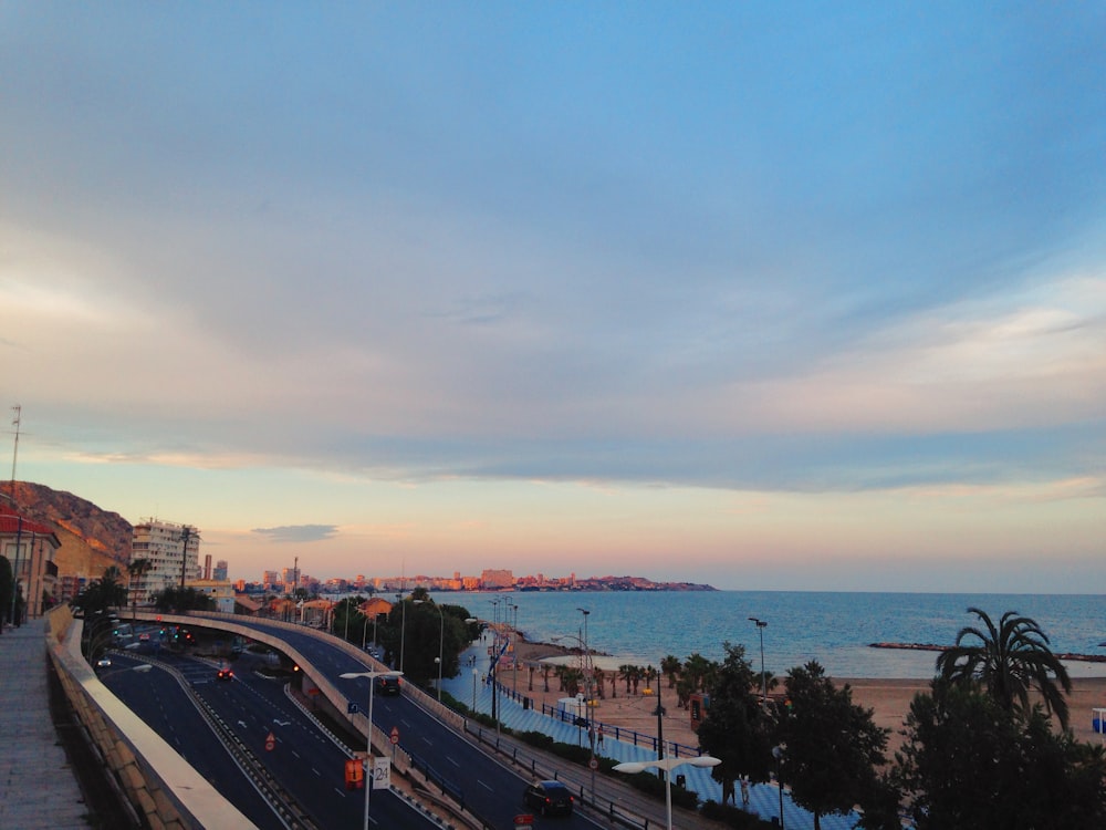 automobili sulla strada vicino allo specchio d'acqua durante il tramonto