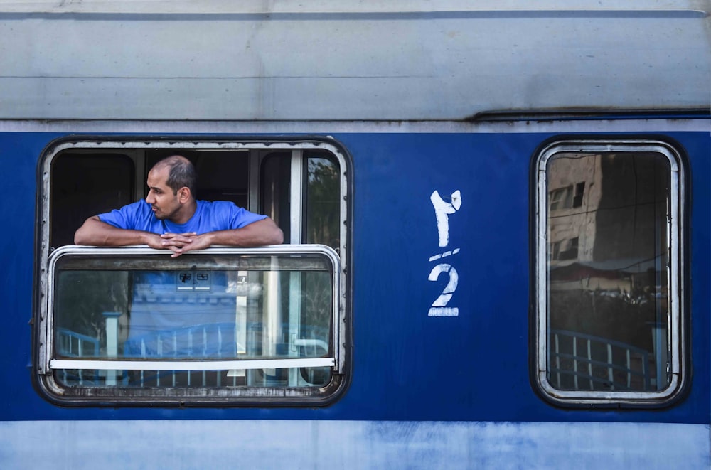 man in blue jacket sitting on blue and white bus