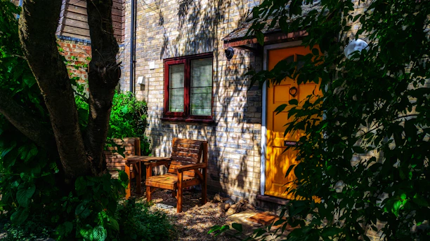Cozy wooden dog house nestled in a sunny garden corner with blooming flowers.
