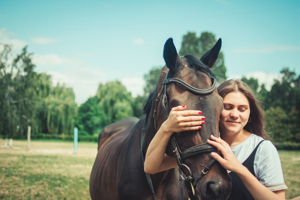 woman in black tank top holding brown horse during daytime